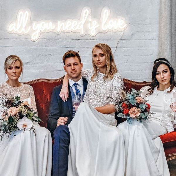 All You Need is Love white neon flex sign on a wedding photo wall behind the bridal party - from Custom Neon
