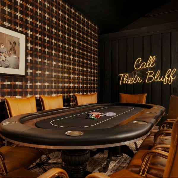 Call Their Bluff LED neon sign on a dark wooden wall behind a gaming table in a masculine room decorated in tans, blacks and browns - CUSTOM NEON™ x SOMERLED COLLECTION