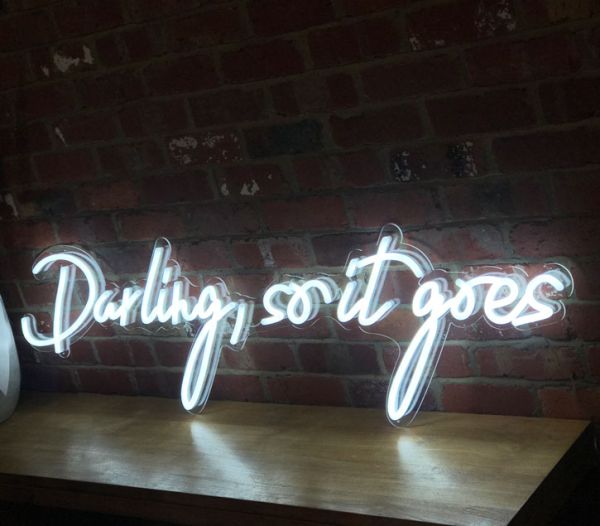 Beautiful cursive neon word sign * Darling, so it goes * shown against exposed brick wall
 - photo from CustomNeon.com