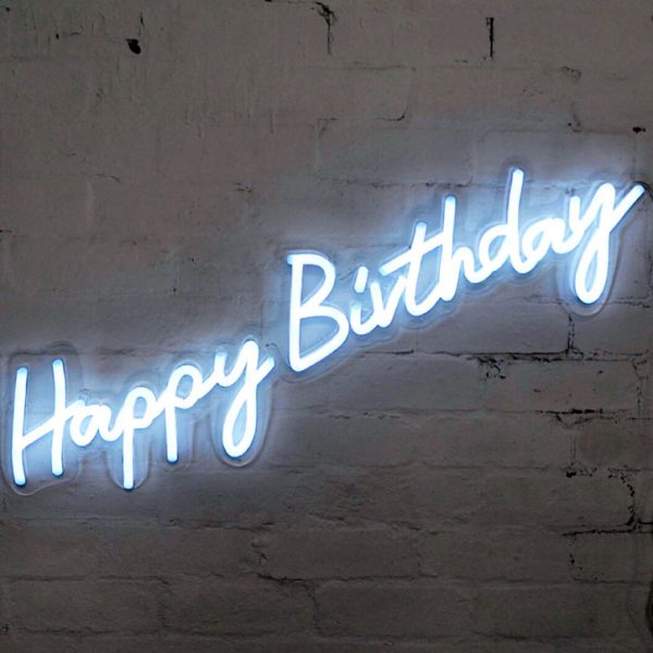 * Happy Birthday * is a lightweight, portable neon sign in modern cursive font, shown against a brick wall. 
