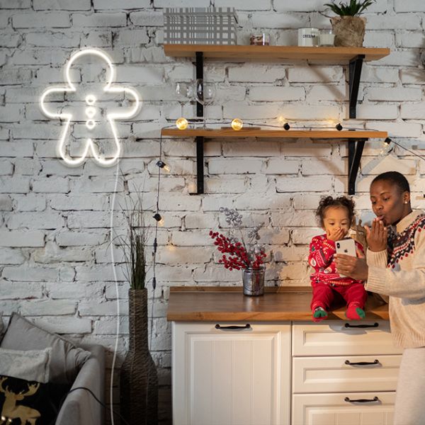 Light Up Gingerbread Man by CUSTOM NEON® shown in white on brick wall near Christmas lights & decorations