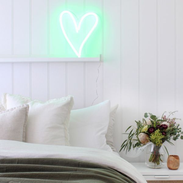 A little love heart in green shown as bedroom decor, on a shelf against a white wall - photo from CustomNeon.com
