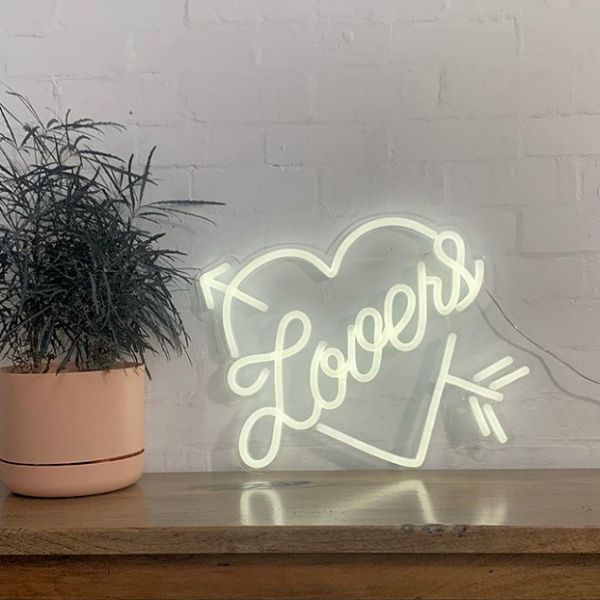 Heart shaped neon flex with Lovers written inside shown  on side table - from Custom Neon®