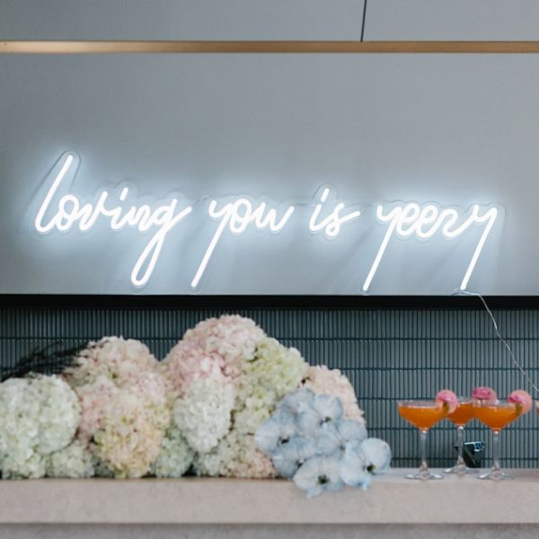 Loving you is yeezy LED neon wedding sign shown in white behind the bar - photo from CustomNeon.com Custom Neon® @customneon