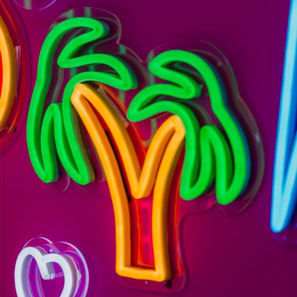 Custom Neon® Palm Tree Neon Light shown illuminated on a dark background in dim light
