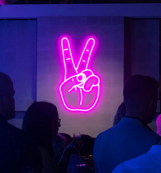 Neon Peace Sign aesthetic neon light shown wall mounted in a restaurant - photo from CustomNeon.com
