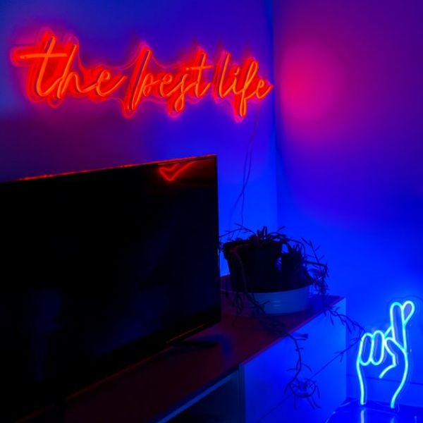 The Best Life red neon flex sign shown above a flatscreen TV in a living room @customneon