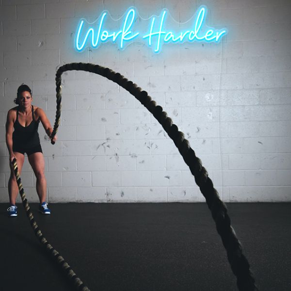 Work Harder light blue CUSTOM NEON® signs on brick wall in fitness/boxing studio