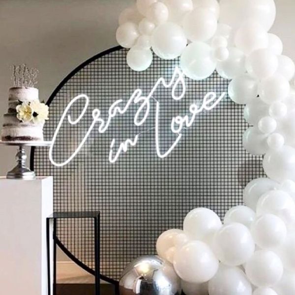 Crazy In Love Wedding Sign in brilliant LED neon flex shown in white with balloons and a wedding cake - photo from CustomNeon.com