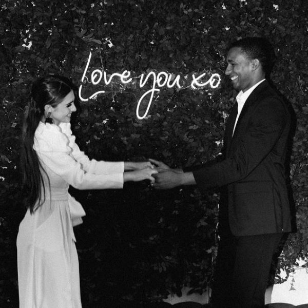 Love You XO LED neon sign on green wall while happy couple hold hands - sign by CustomNeon.com / photo by candileonardphotography.com