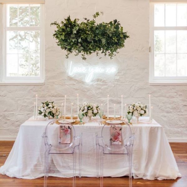 Love you xo white lightup sign on a white wall behind a wedding cake and table decor - from Custom Neon