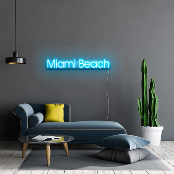 Miami Beach Light Sign by CUSTOM NEON® shown in ice blue against dark grey wall above grey blue couch