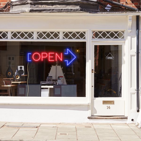Neon light open sign in red with an oversized blue arrow shown in a shop window - from CustomNeon.com