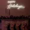 CUSTOM NEON® Happy Holidays light sign above the fireplace with its Christmas stockings, candles and decorations