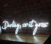 Beautiful cursive neon word sign * Darling, so it goes * shown against exposed brick wall
 - photo from CustomNeon.com