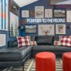 Powder to the People white LED neon sign on a blue feature wall surrounded by framed skiing related paintings and prints - CUSTOM NEON™ x SOMERLED COLLECTION