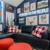 Powder to the People white LED neon sign on a blue feature wall above a black leather couch in a living room - CUSTOM NEON™ x SOMERLED COLLECTION