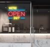 WE'RE OPEN 24/7 in brilliant yellow and red, with bright blue lines shown in a cafe window - from CustomNeon.com