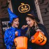 CUSTOM NEON® Spooky Jack O Lantern in pumpkin orange on a dark door surrounded by Halloween decorations