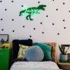 Personalized LED neon child's name sign with dinosaur background shown in child's bedroom- from CustomNeon.com