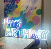 Happy Birthday is a double line LED neon word sign in two fonts on clear acrylic backboard that is cut around the shape.
