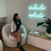 Inhale Exhale Custom Neon® wall sign shown illuminated on a living room wall