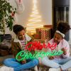 Merry Christmas Red & Green LED Neon Sign by CUSTOM NEON® held by smiling girls with a Nativity scene, presents & decorations in the background.