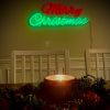 Red & green Merry Christmas neon light by CUSTOM NEON® wall mounted with a festive candle and holly centerpiece in the foreground.
