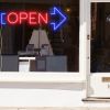 Neon light open sign in red with an oversized blue arrow shown in a shop window - from CustomNeon.com