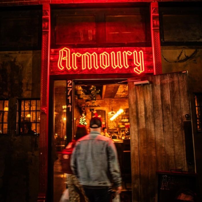 Red Armoury LED neon sign above the bar entrance at night in Deep Ellum, Dallas