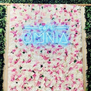 Custom Neon® tropical blue logo light sign on a flower wall @cafeomnia by 