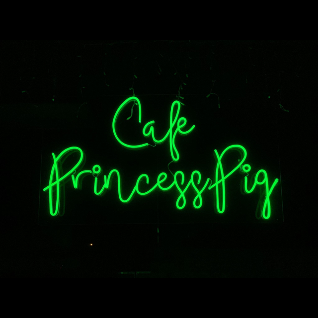Green Custom Neon® name sign in the window of @cafeprincesspig