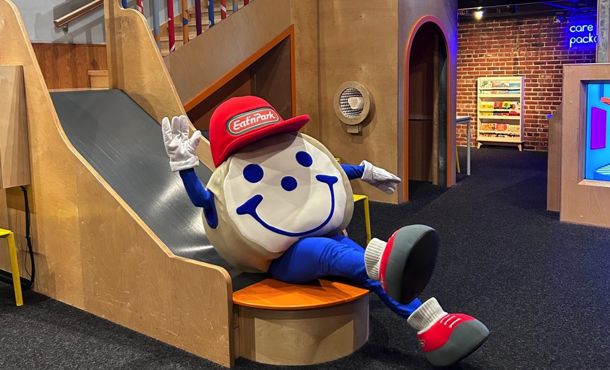 Blue Custom Neon® sign reading care packages installed on a brick wall @pghkids