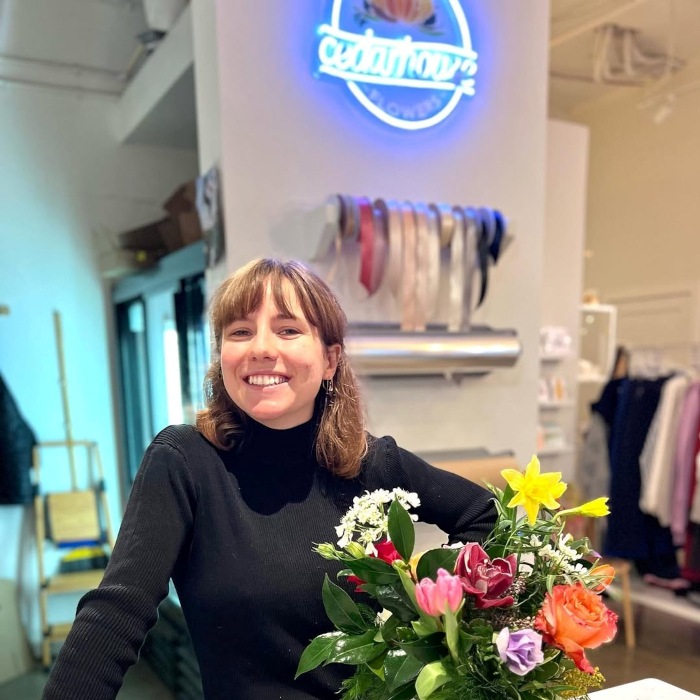 Custom Neon® UV Print logo on a white wall with the florist in the foreground @cedarhouseflowers