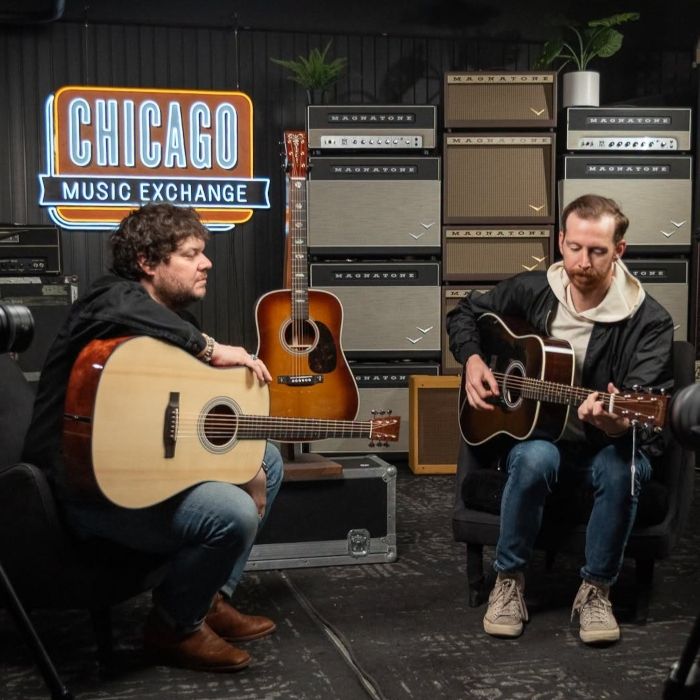 Chicago Music Exchange Custom Neon® sign above two musicians playing acoustic guitars