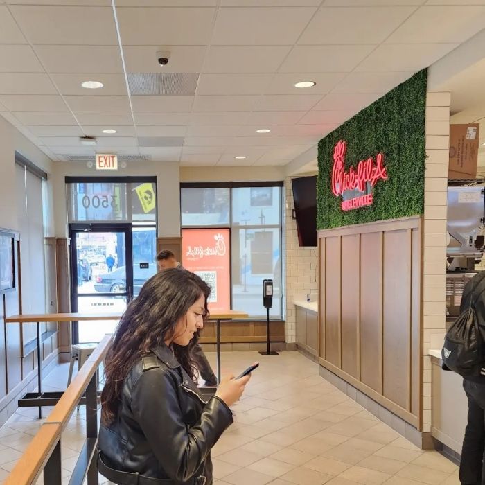 Chick-fil-A Custom Neon® logo sign glowing on a green wall inside a Chicago restaurant