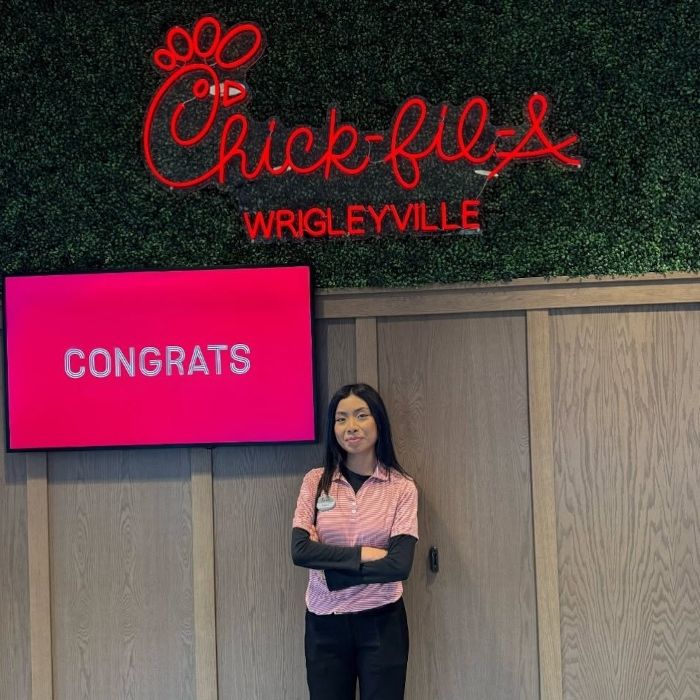 Chick-fil-A Wrigleyville Custom Neon® sign above an employee standing under a congrats screen