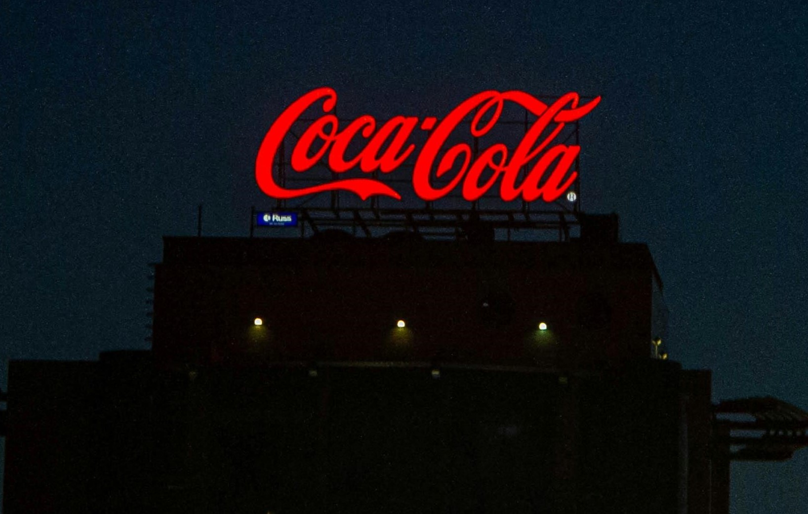 Red Coca Cola sign on the roof of a building - photo by Александра Аношко @pexels