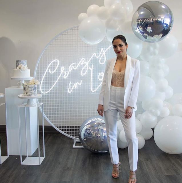 Custom Neon® white Crazy in Love sign surrounded by a balloon arch and wedding cake @decorandfiesta