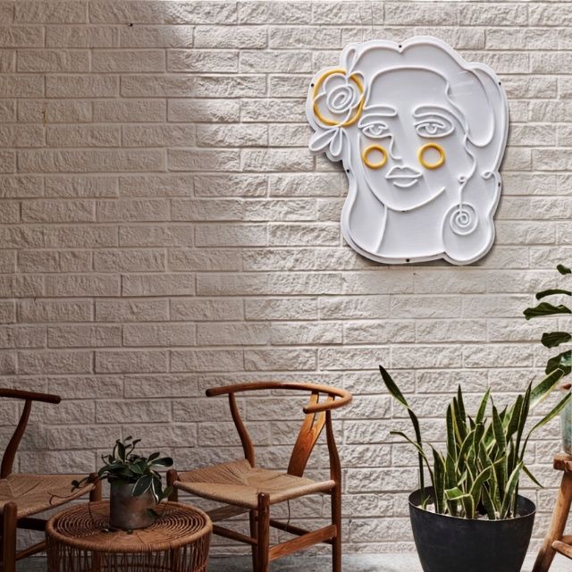 Delbar's lady logo in white and orange LED neon flex on a white brick wall beside cafe seating