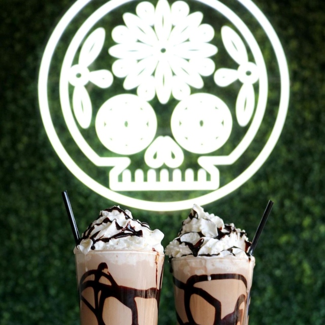 White Custom Neon® Mexican sugar skull logo above milkshakes @delsurtacqueria
