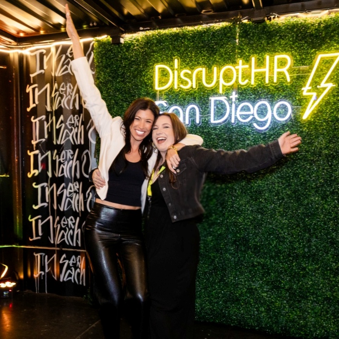 Yellow and white Custom Neon® Disrupt HR San Diego event sign on a grasswall