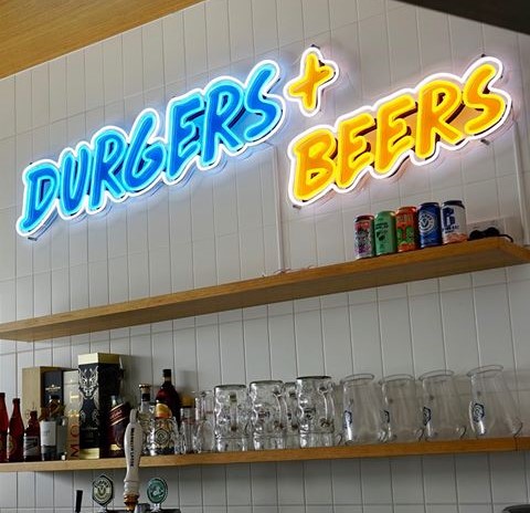 Custom Neon® tagline sign in ice blue & yellow LED neon on UV printed backboard for @st.burgs