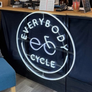 White logo sign by Custom Neon® for reception @everybodycycle