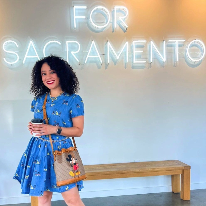 Large white Custom Neon® sign reading For Sacramento on a white wall with a woman in the foreground @projectchurchsac