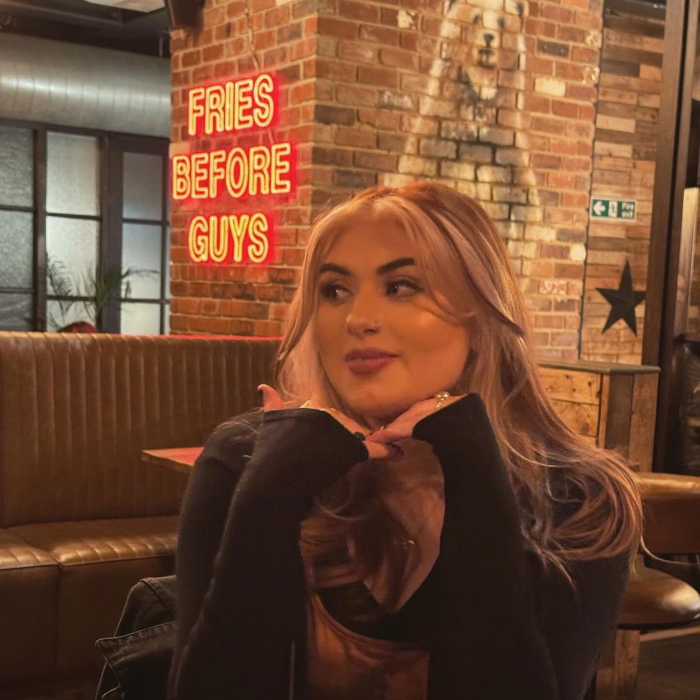 Fries Before Guys Custom Neon® sign in red LED neon on a brick wall in the background of a selfie @brewskirestaurants