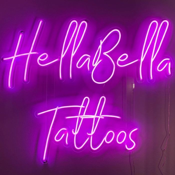 HellaBella Tattoos purple script LED neon sign glowing on the studio wall