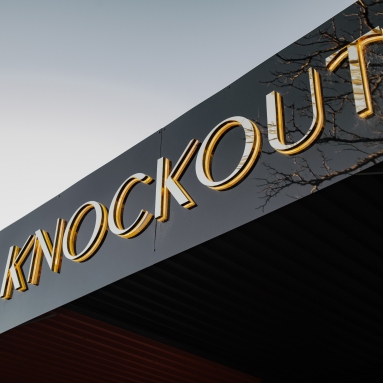 Close up of back lit gold mirrored channel letters above the entrance to the Knockout Brows salon