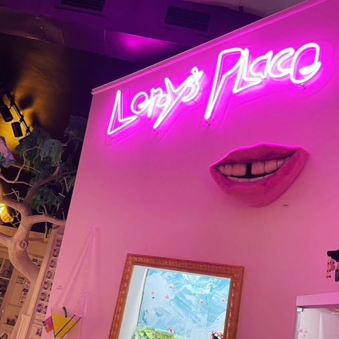 Pink Custom Neon® 'Lenny's Place' sign in an eclectic art and gift shop filled with quirky sculptures and shelves of curios