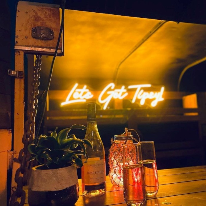 Let's get tipsy yellow Custom Neon® quote sign in a mobile bar trailer @thetipsytire